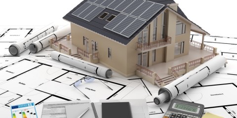 Haus inmitten von Bauplänen und Planungsutensilien.